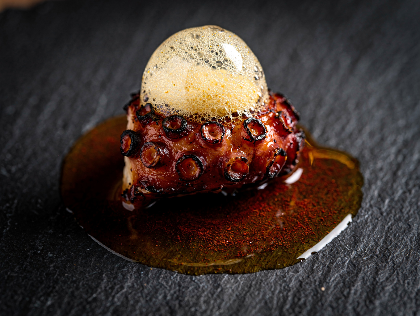 Charred octopus tentacle plated over velvety chickpea puree with herbs